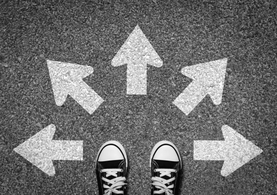 רקע אפור, נעלי סניקרס שחור לבן, חיצים בלבן לכל הכיוונים שלפני הנעליים